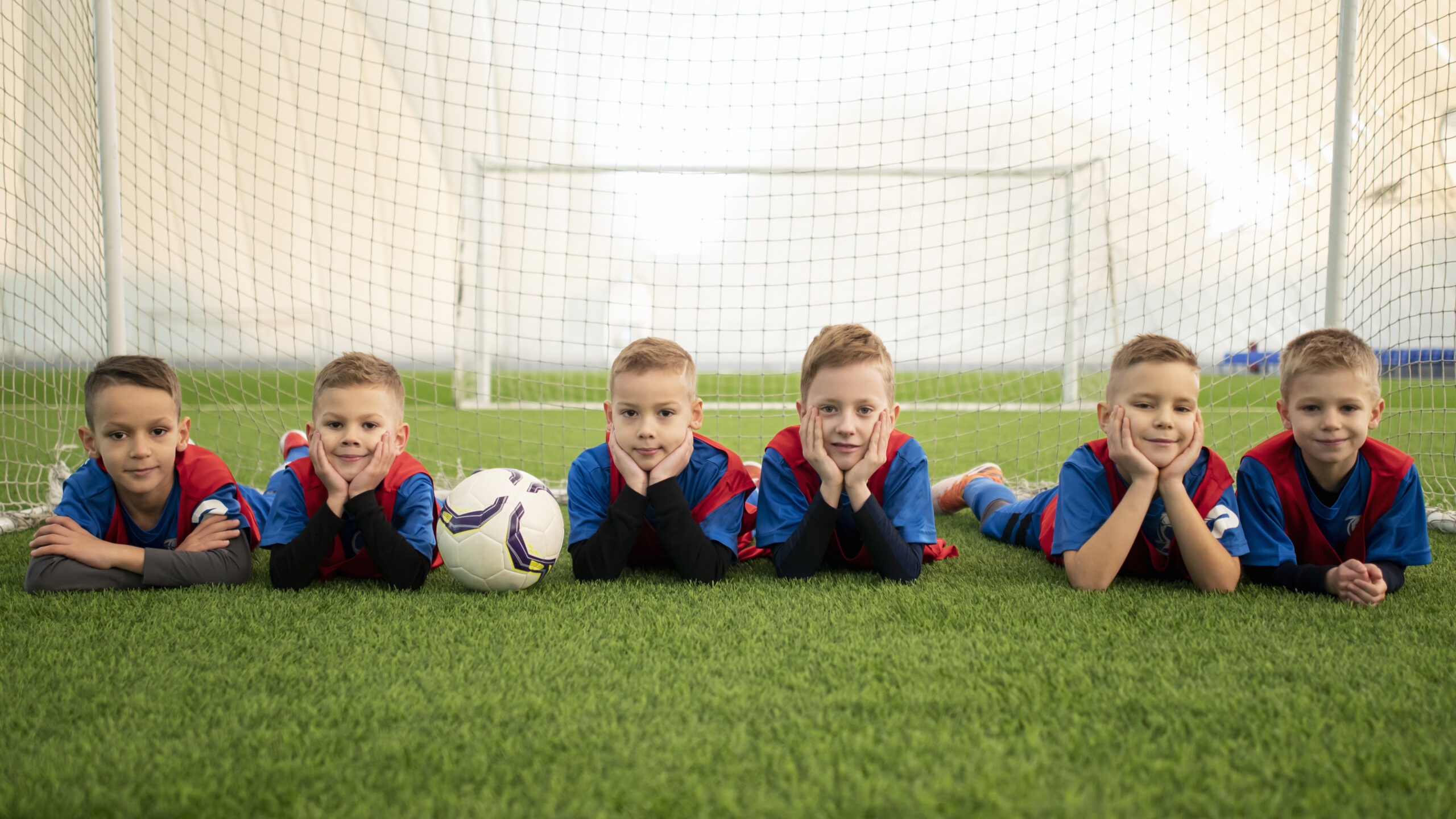 Kids Laying on Grass in front soccer goal