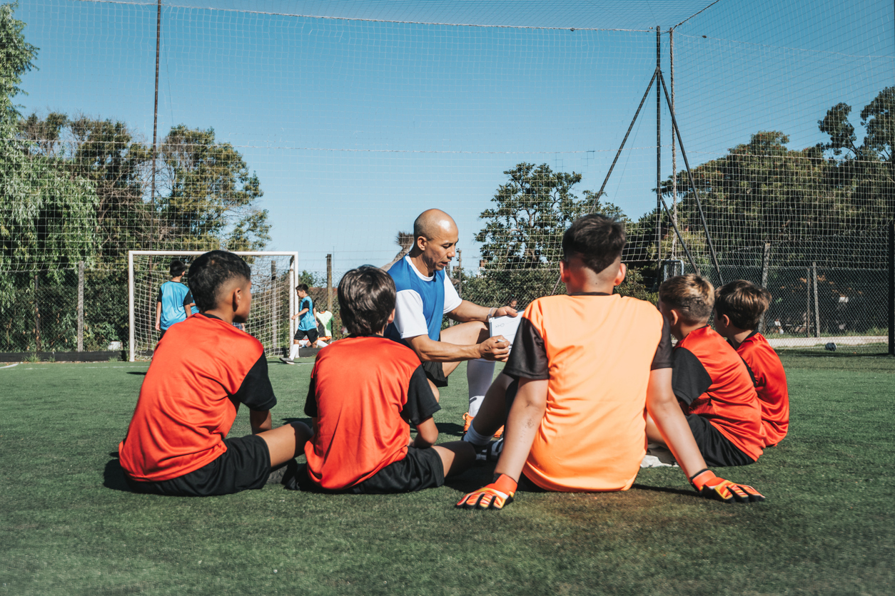 adult coach training boy soccer team on soccer field